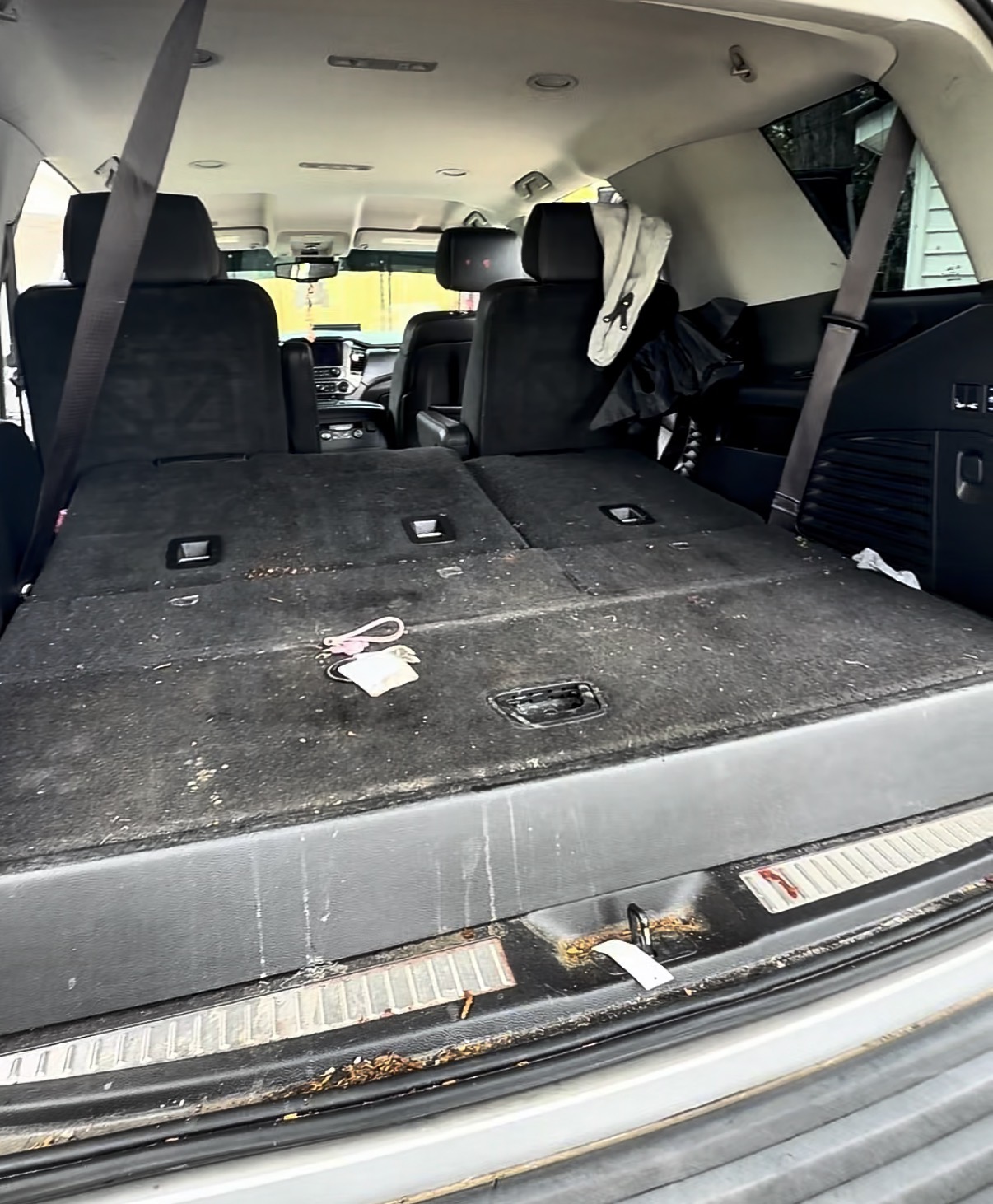 Dirty SUV cargo area with folded rear seats before cleaning